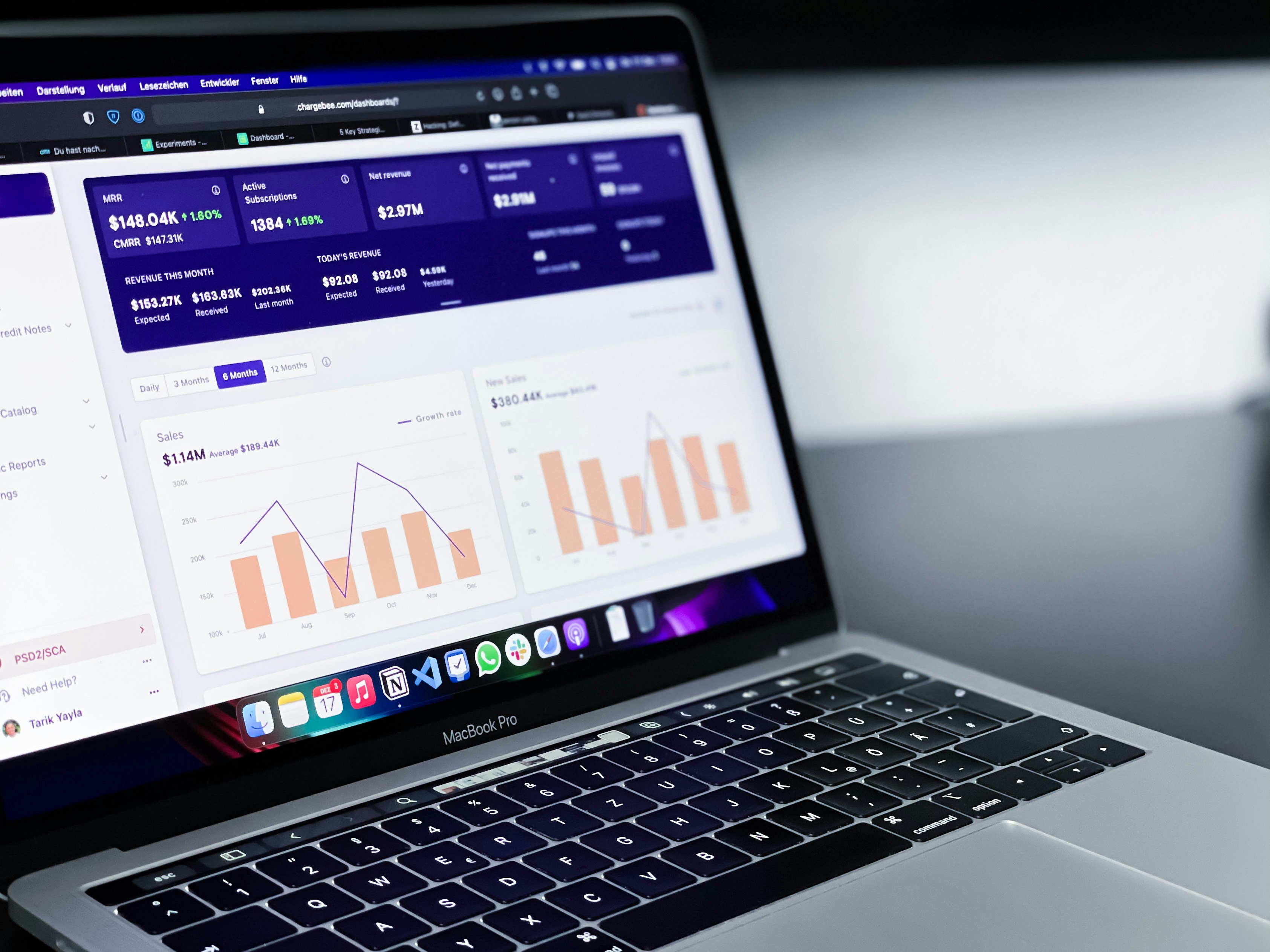 A person analysing a company's financial performance on a business analytics dashboard, which is displayed on a MacBook Pro. The dashboard shows metrics for monthly recurring revenue (MRR) and sales growth.